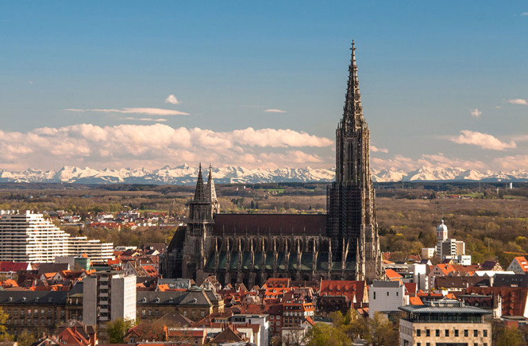 Das riesige Ulmer Münster mit den Alpen im Hintergrund